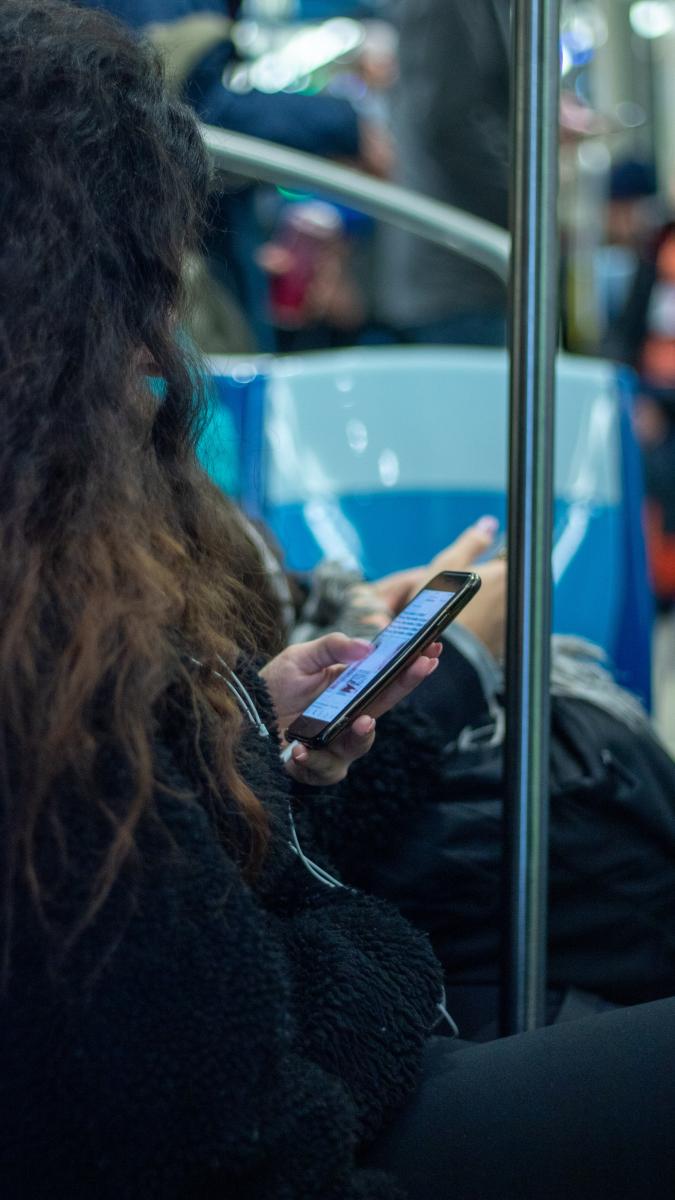 Woman on train listening through smartphone