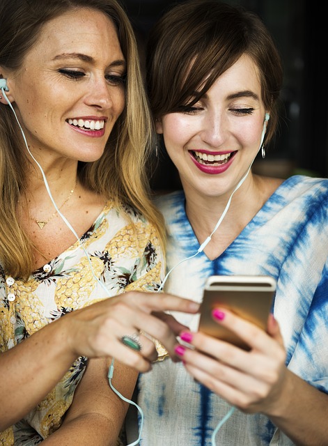 Two girls with earbuds connected to phone