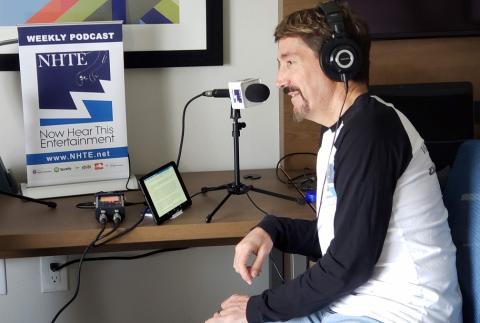 Profile shot of Bruce Wawrzyniak wearing headphones at a microphone recording the podcast