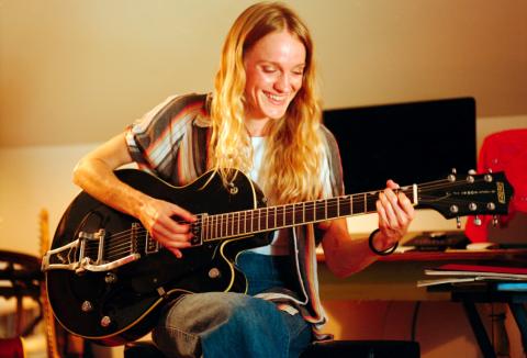 Hannah Delynn seated playing guitar