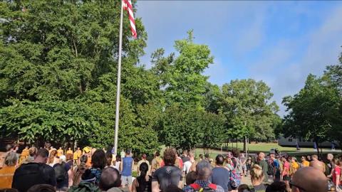 A crowd stands and looks up at the American flag during the national anthem