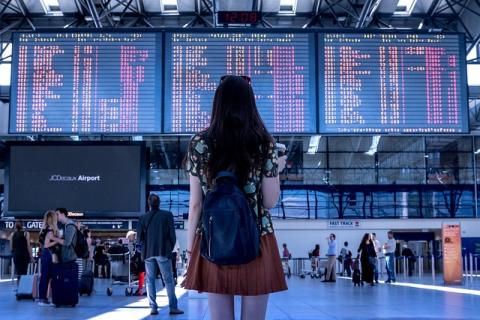 Girl standing in airport looks up at arrival and departure screens