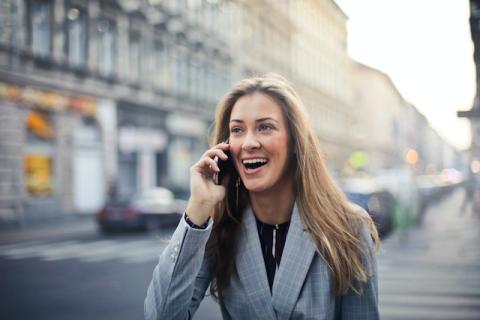 Long blonde-haired girl on phone outside with surprised smiling look