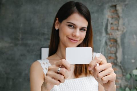 Girl holding white business card out towards camera