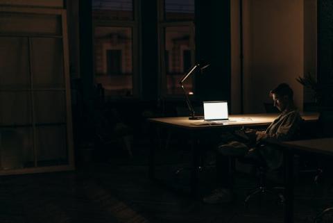 Guy sitting at his desk alone in a dark office seemingly late at night