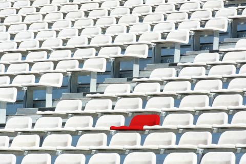 One red seat in stadium full of white seats