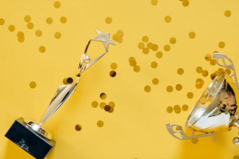 Trophies and confetti lay against a gold colored background