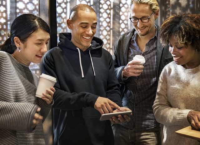 Four smiling people looking at tablet