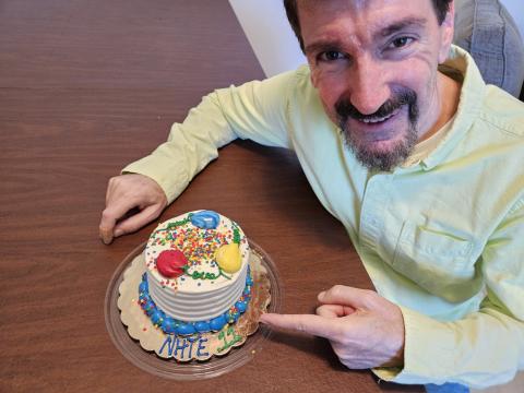 Bruce Wawrzyniak with a cake that has NHTE 11 written around the bottom front