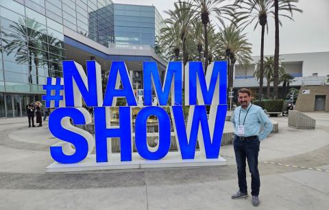Bruce Wawrzyniak stands alongside a lifesize #NAMM SHOW sign in Anaheim