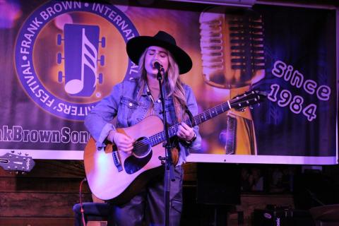 Kaitlyn Croker sings and plays guitar while performing on stage at the FloraBama