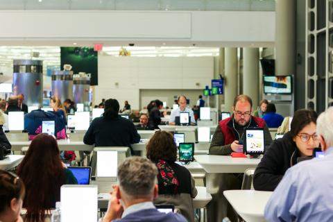 A busy newsroom with men and women seated and looking at computers