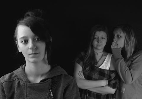 Two girls whispering behind a third girl Two girls whispering behind a third girl
