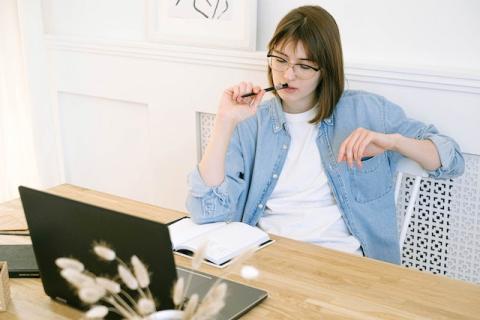 Girl seated and staring at laptop while thinking