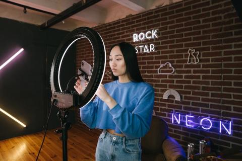 Girl with long black hair holding smartphone next to ring light Girl with long black hair holding smartphone next to ring light